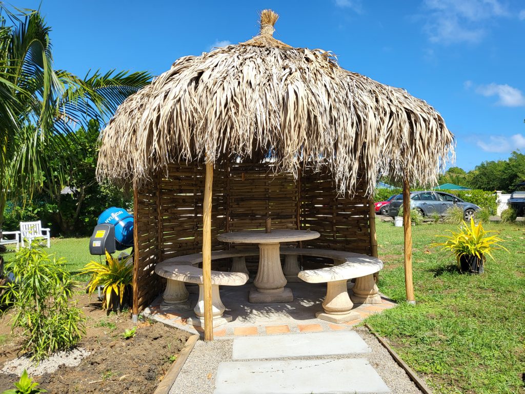 Carbet en paille avec table et bancs dans le jardin